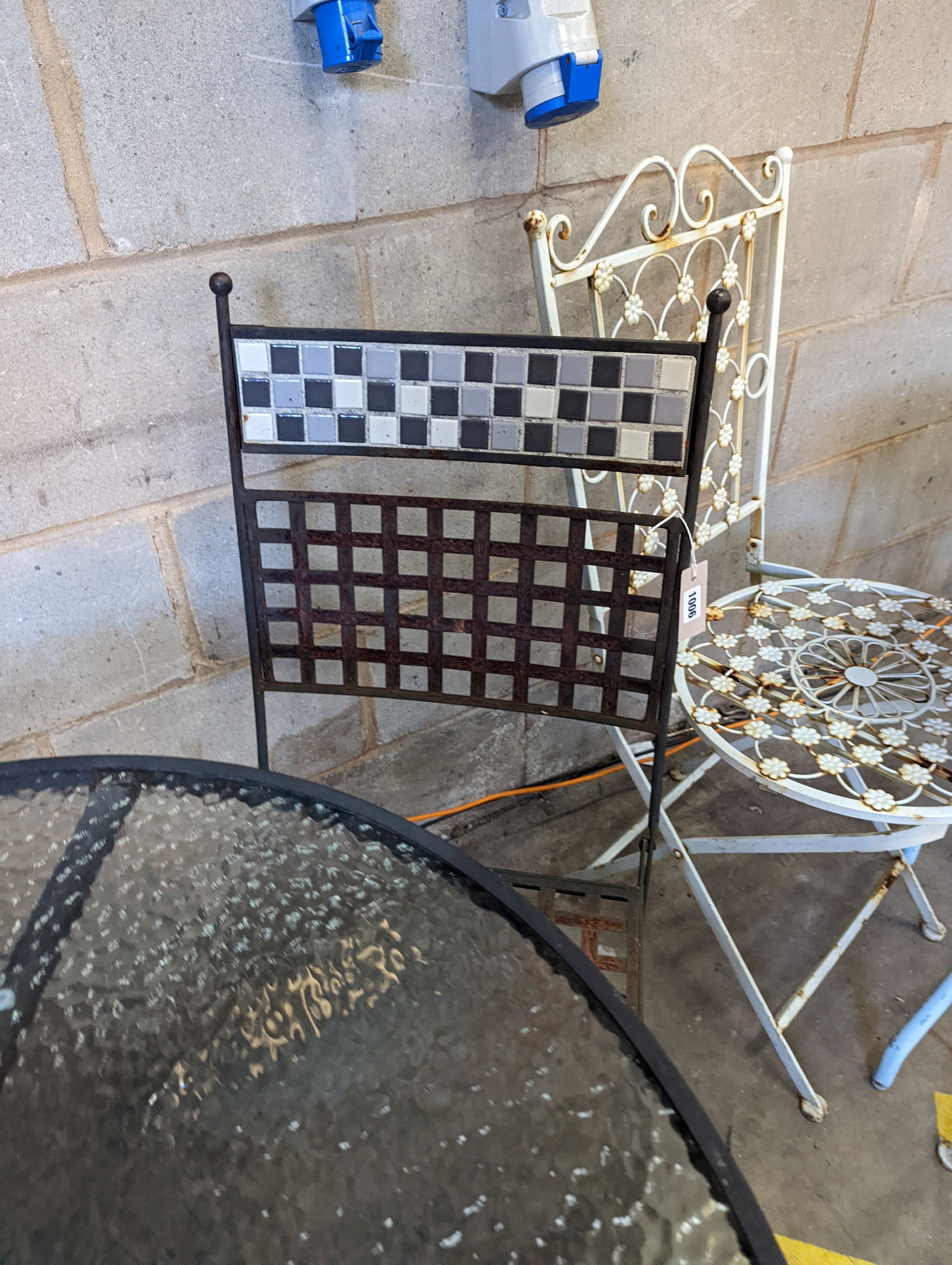 A circular glass top garden table, diameter 80cm, height 71cm and four metal folding garden chairs